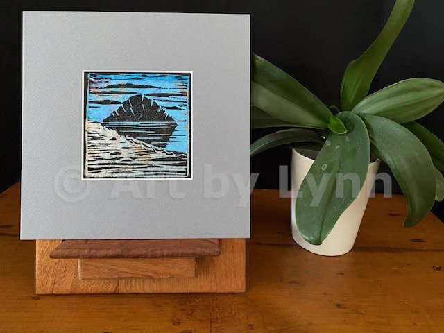 Relief print, with chine colle of the Rock in Morro Bay, next to a house plant.